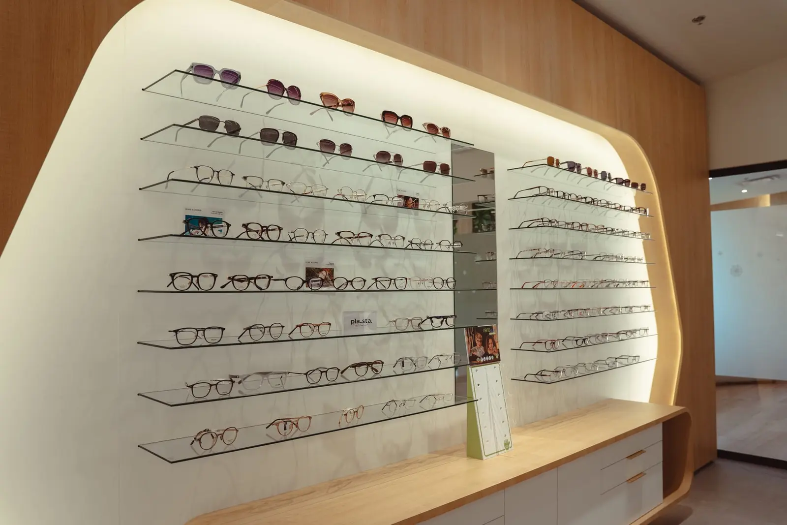 A lit eyewear wall in warm oak at the Claye optical